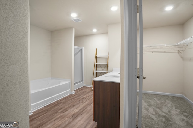 bathroom with hardwood / wood-style floors, independent shower and bath, and vanity