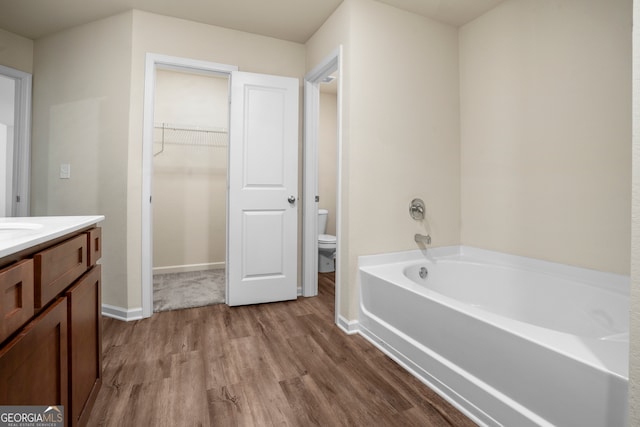 bathroom with toilet, vanity, hardwood / wood-style flooring, and a bathing tub