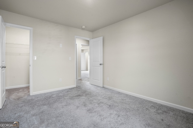 unfurnished bedroom featuring carpet floors, a walk in closet, and a closet