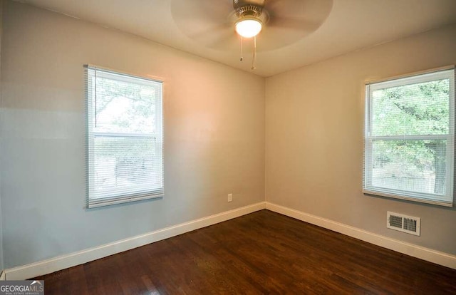 spare room featuring ceiling fan, a healthy amount of sunlight, and dark hardwood / wood-style flooring