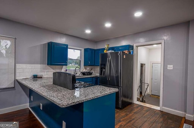 kitchen with sink, a breakfast bar area, blue cabinets, stainless steel fridge, and dark hardwood / wood-style flooring