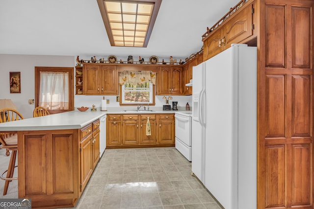 kitchen with white appliances, sink, a breakfast bar, and kitchen peninsula