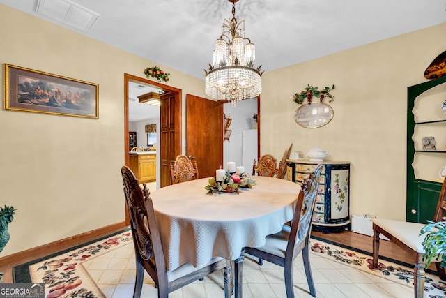 dining area with light hardwood / wood-style floors and an inviting chandelier