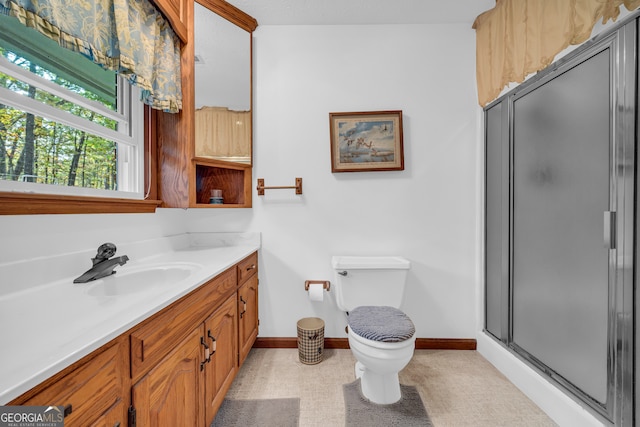 bathroom featuring vanity, toilet, and a shower with door