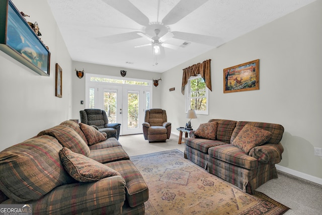 living room with a textured ceiling, french doors, light carpet, and ceiling fan