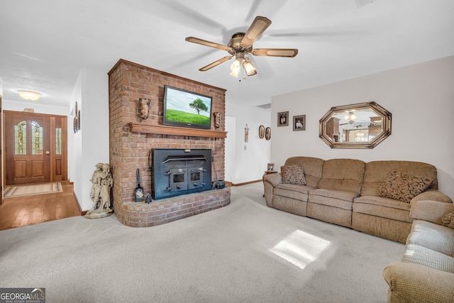 living room with light hardwood / wood-style floors, ceiling fan, and a wood stove