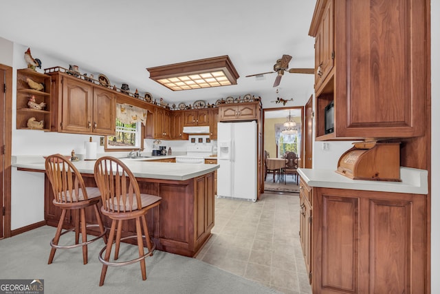 kitchen with sink, a breakfast bar, kitchen peninsula, ceiling fan with notable chandelier, and white appliances