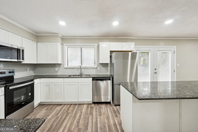 kitchen with stainless steel appliances, light wood-type flooring, a textured ceiling, sink, and white cabinets