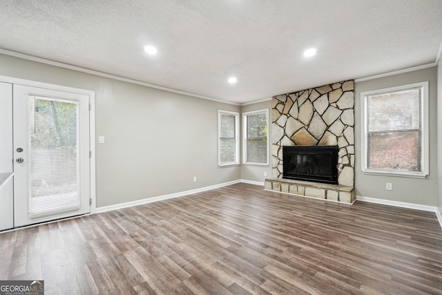 unfurnished living room featuring hardwood / wood-style floors, a fireplace, a healthy amount of sunlight, and ornamental molding