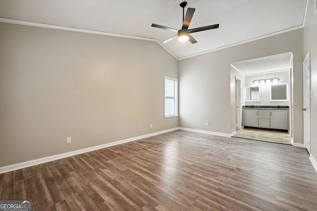 interior space with ornamental molding, wood-type flooring, vaulted ceiling, and ceiling fan