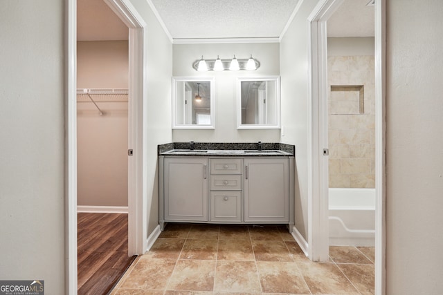 bathroom featuring vanity, a textured ceiling, ornamental molding, and wood-type flooring