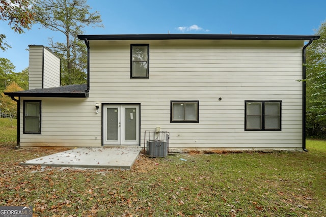 rear view of house with central air condition unit, a patio area, a lawn, and french doors