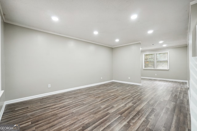 spare room featuring dark wood-type flooring and crown molding