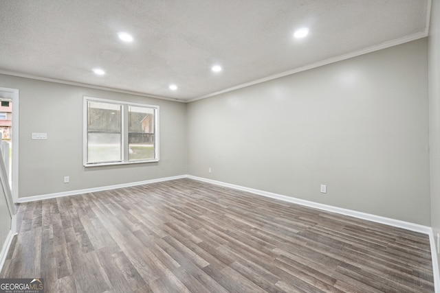 empty room featuring wood-type flooring, a textured ceiling, and crown molding