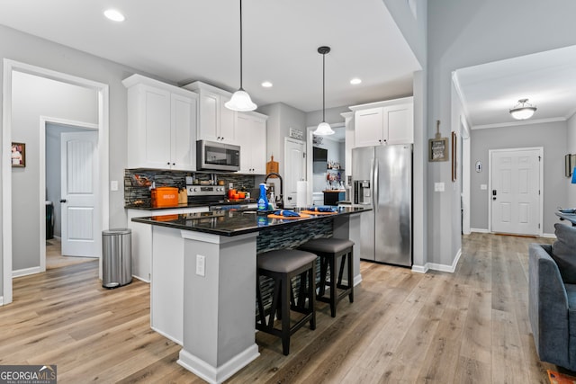 kitchen with light wood-type flooring, white cabinets, a kitchen island with sink, and stainless steel appliances