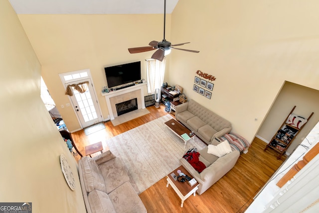 living room with ceiling fan, light hardwood / wood-style flooring, and high vaulted ceiling