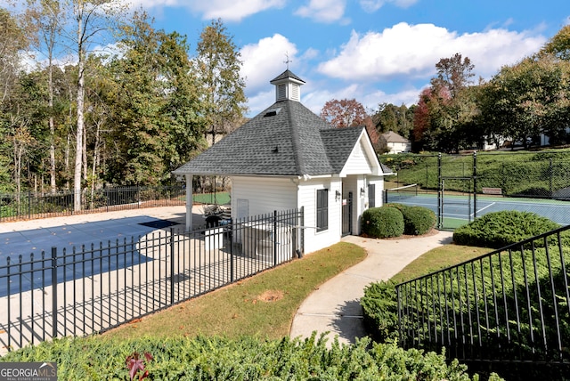 view of swimming pool with tennis court and a lawn