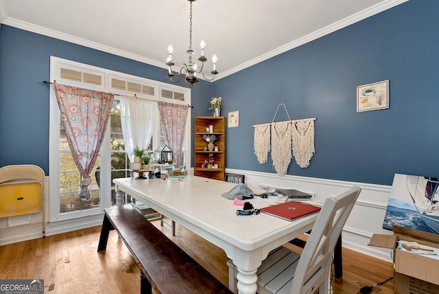 dining area with hardwood / wood-style flooring, an inviting chandelier, and crown molding