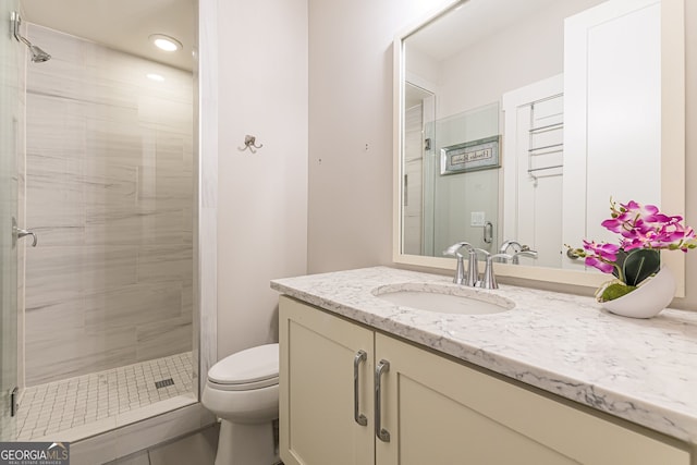 bathroom with vanity, toilet, and a shower with door