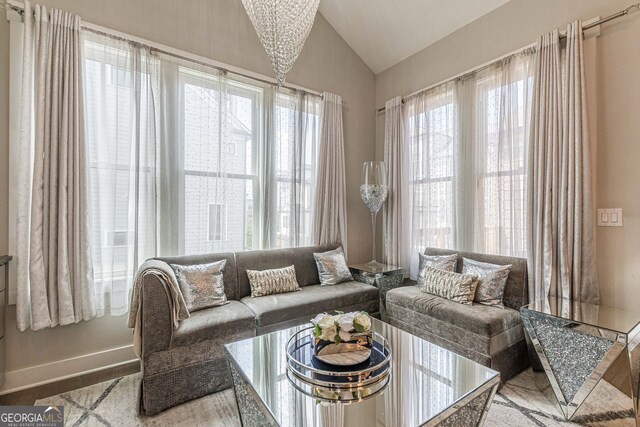 sitting room featuring light hardwood / wood-style floors, lofted ceiling, and a notable chandelier