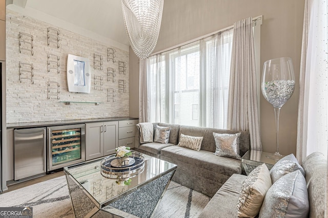 living room with hardwood / wood-style floors, bar, beverage cooler, and an inviting chandelier