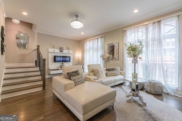 living room featuring dark hardwood / wood-style flooring, a tiled fireplace, and ornamental molding