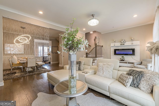 living room with dark wood-type flooring, crown molding, and a notable chandelier