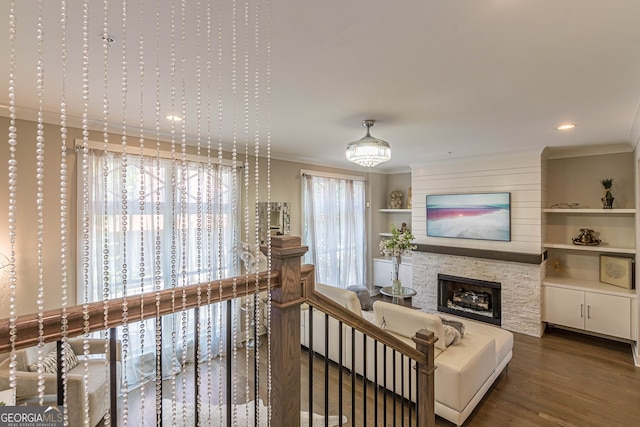 living room featuring dark hardwood / wood-style flooring, built in features, ornamental molding, and a fireplace