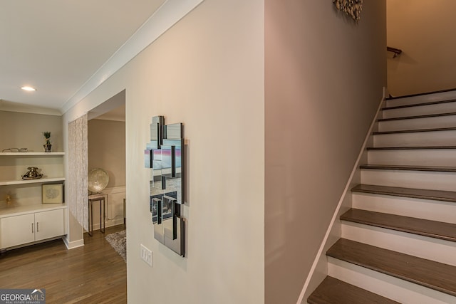 stairway with ornamental molding and wood-type flooring