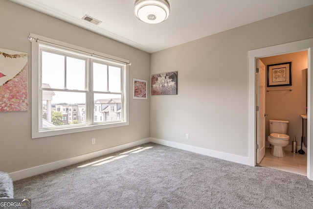 bedroom with ensuite bath and carpet