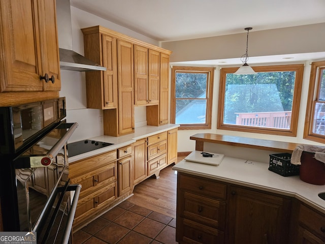 kitchen with black appliances, a healthy amount of sunlight, decorative light fixtures, and wall chimney range hood