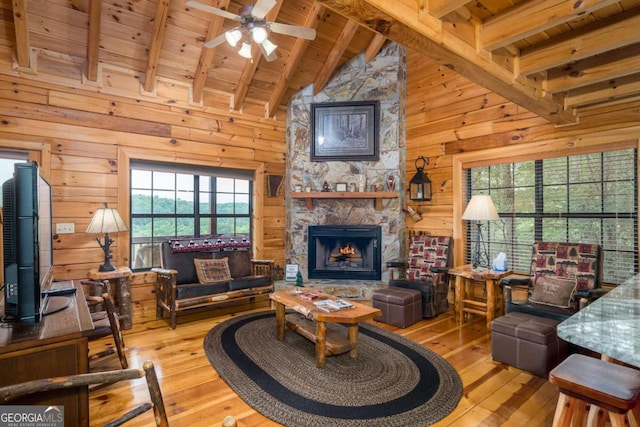 living room with wood walls, light wood-type flooring, and beam ceiling