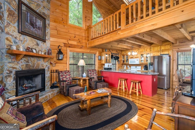 living room featuring a high ceiling, beam ceiling, wood ceiling, and light hardwood / wood-style flooring