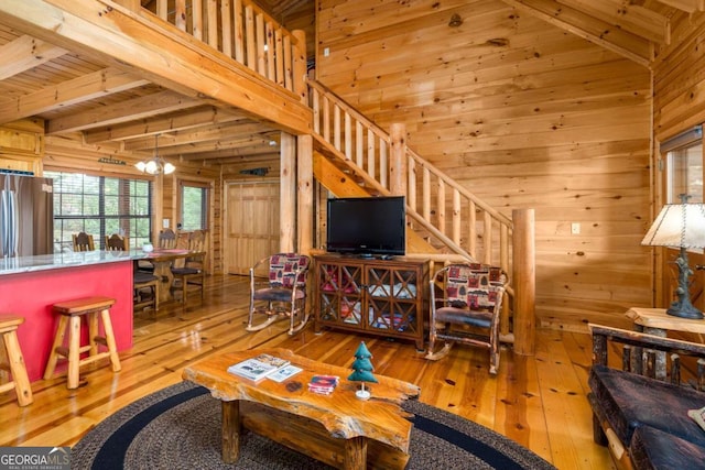 living room with light wood-type flooring, beam ceiling, wooden walls, an inviting chandelier, and wooden ceiling