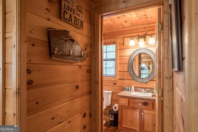 bathroom with vanity, wooden walls, toilet, and wood ceiling