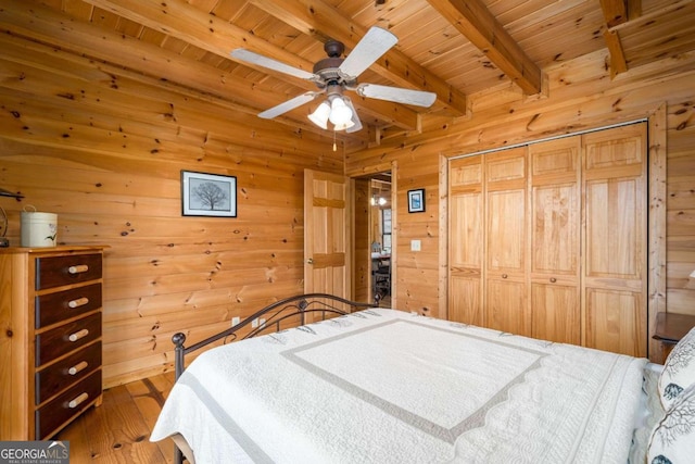 bedroom with wooden ceiling, hardwood / wood-style flooring, beamed ceiling, ceiling fan, and a closet