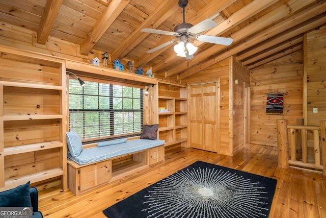 interior space featuring vaulted ceiling with beams, wood walls, wooden ceiling, ceiling fan, and light wood-type flooring