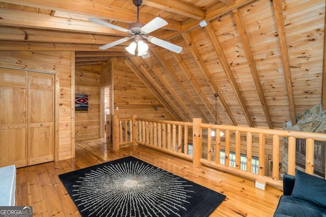 unfurnished room with ceiling fan, wood-type flooring, wood ceiling, vaulted ceiling with beams, and wooden walls