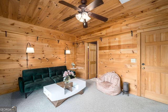 carpeted living room featuring wooden walls and ceiling fan