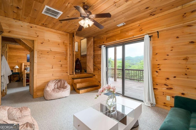 living room with carpet flooring, wood walls, and ceiling fan