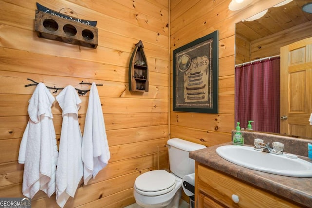 bathroom featuring vanity, wooden walls, and toilet