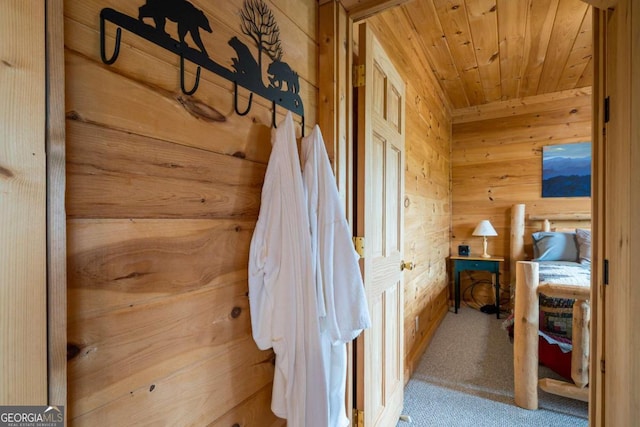 corridor featuring carpet floors, wood walls, and wood ceiling