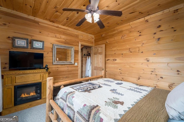 carpeted bedroom with wood walls, wood ceiling, and ceiling fan