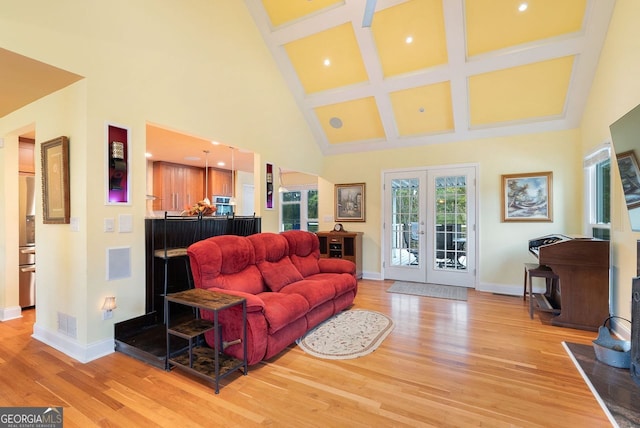 living room with french doors, light hardwood / wood-style floors, beamed ceiling, and a high ceiling