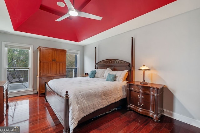 bedroom with access to exterior, dark wood-type flooring, ceiling fan, and a raised ceiling