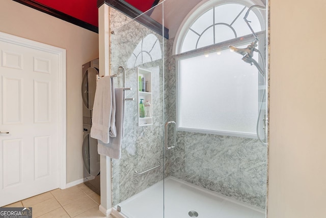 bathroom featuring walk in shower, tile patterned flooring, and stacked washing maching and dryer