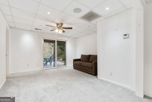 living area featuring a paneled ceiling, light carpet, and ceiling fan