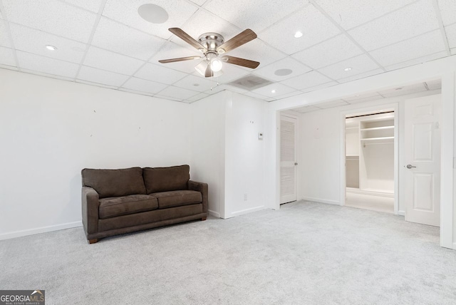 living area featuring a paneled ceiling, light carpet, and ceiling fan