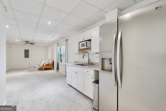 kitchen with stainless steel fridge, white cabinetry, light carpet, sink, and ceiling fan