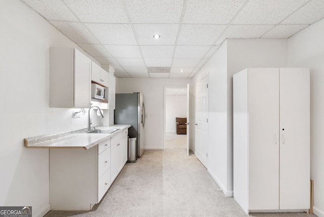 kitchen with white cabinets, light carpet, and sink